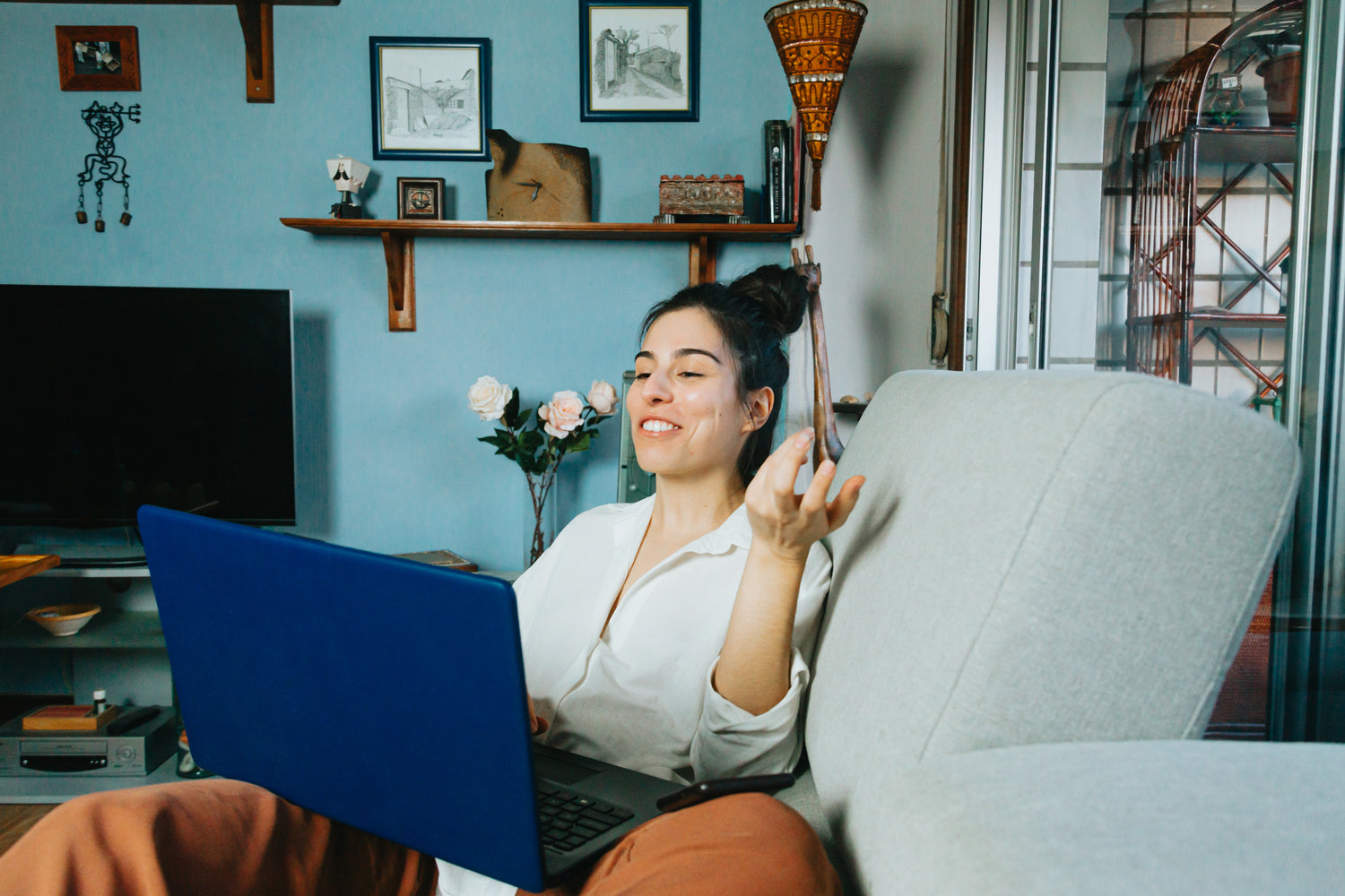 Woman on a couch partaking in a video call on her laptop.