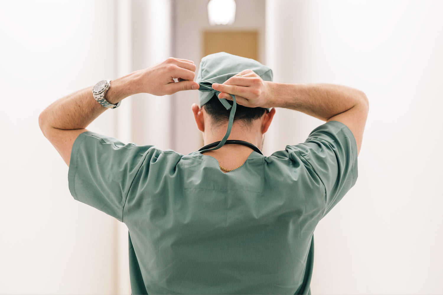 Doctor tying on surgical cap in preparation.