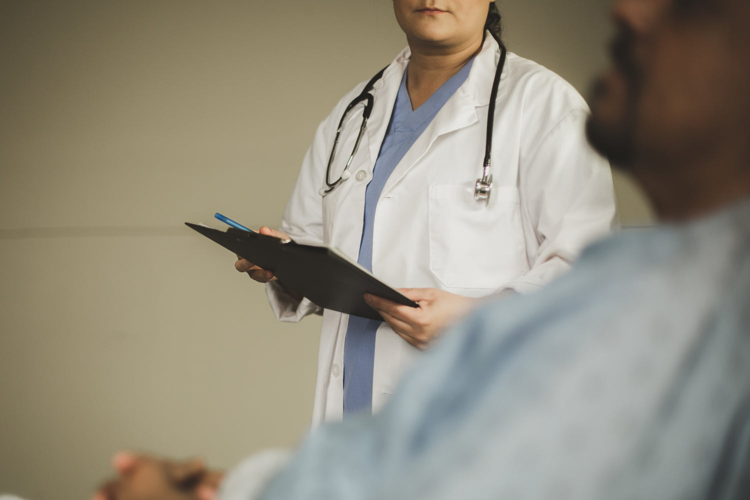 Doctor views patient while holding a clipboard. 